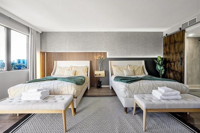 bedroom featuring visible vents, a barn door, and wood finished floors