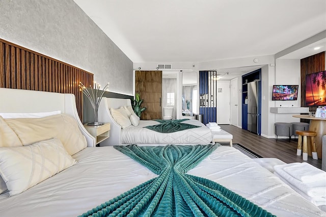 bedroom featuring stainless steel fridge, wood finished floors, and visible vents