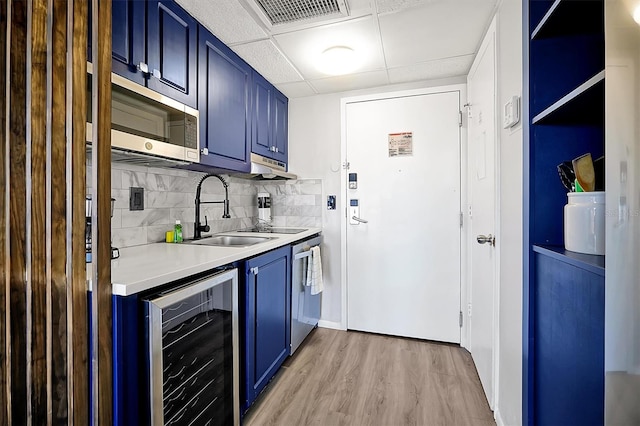 kitchen featuring blue cabinetry, a sink, stainless steel appliances, wine cooler, and light countertops