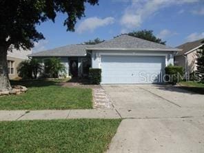 ranch-style house with an attached garage, concrete driveway, and a front yard