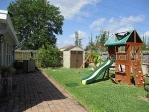 view of play area with an outdoor structure, a storage unit, fence, and a yard