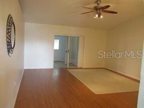 unfurnished room with baseboards, a ceiling fan, and wood finished floors