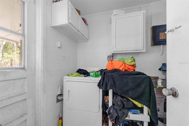 clothes washing area with washer / clothes dryer, cabinet space, and concrete block wall