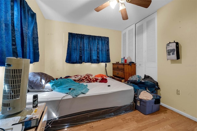 bedroom with wood finished floors, baseboards, a closet, and ceiling fan