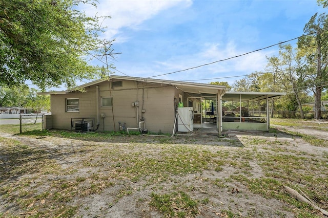 view of outdoor structure featuring fence and a sunroom