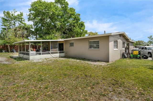 back of property featuring concrete block siding, a yard, and a sunroom