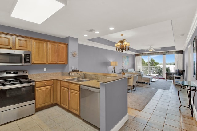 kitchen featuring light tile patterned floors, a peninsula, a sink, stainless steel appliances, and open floor plan