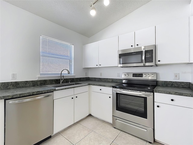 kitchen with dark countertops, stainless steel appliances, lofted ceiling, and a sink