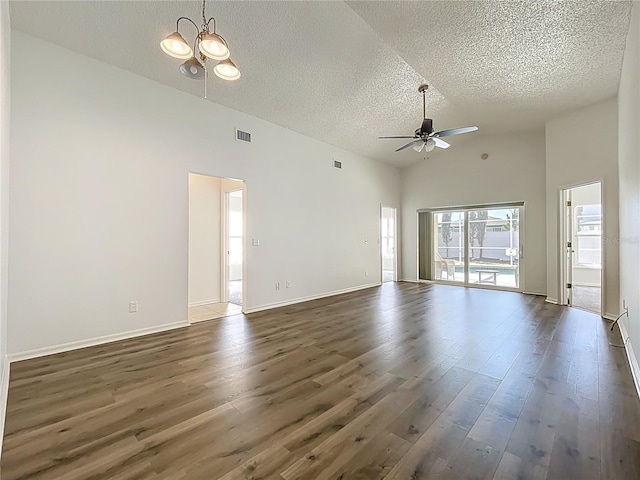 unfurnished living room with visible vents, baseboards, ceiling fan with notable chandelier, a textured ceiling, and dark wood-style flooring