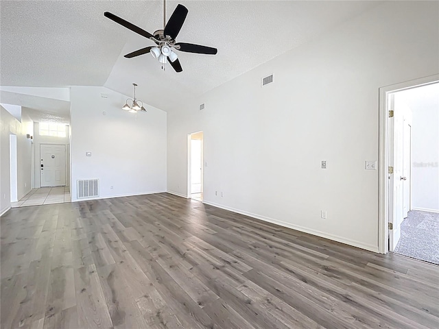 unfurnished living room featuring visible vents, lofted ceiling, a ceiling fan, and wood finished floors