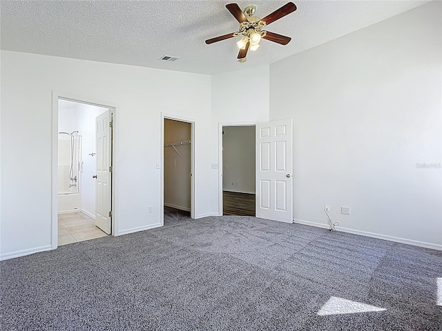 unfurnished bedroom with baseboards, visible vents, vaulted ceiling, a textured ceiling, and carpet flooring