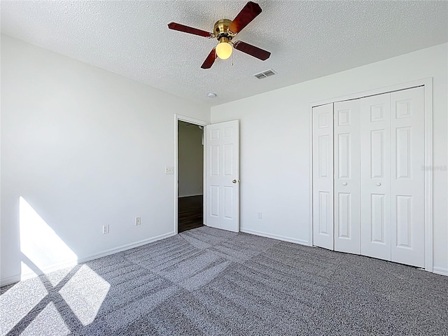 unfurnished bedroom featuring a textured ceiling, carpet flooring, visible vents, and ceiling fan