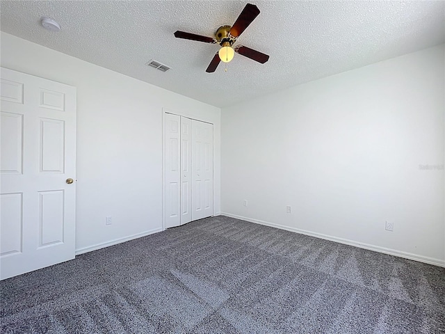 unfurnished bedroom featuring visible vents, a textured ceiling, dark colored carpet, baseboards, and ceiling fan