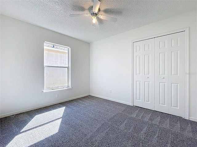 unfurnished bedroom featuring a ceiling fan, baseboards, a closet, a textured ceiling, and dark colored carpet