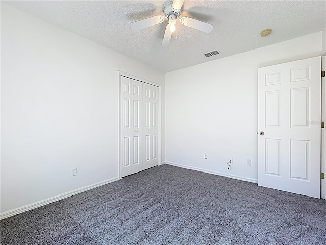 unfurnished bedroom featuring baseboards, visible vents, dark carpet, and a textured ceiling