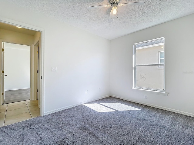 tiled spare room featuring baseboards, carpet floors, a textured ceiling, and a ceiling fan