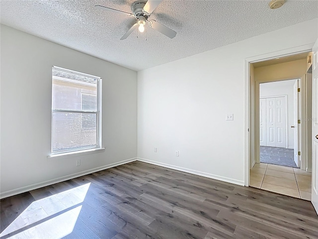 empty room featuring baseboards, a textured ceiling, ceiling fan, and wood finished floors