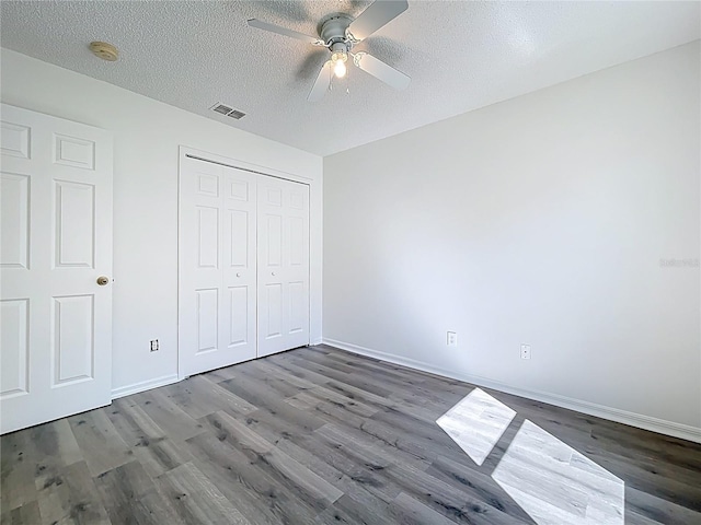 unfurnished bedroom with wood finished floors, visible vents, a closet, and a textured ceiling