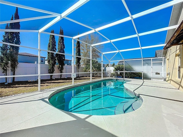 view of swimming pool featuring glass enclosure, a patio, a fenced backyard, and a fenced in pool