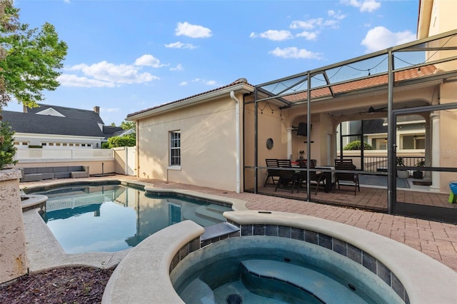 view of pool featuring a pool with connected hot tub, fence, glass enclosure, ceiling fan, and a patio area