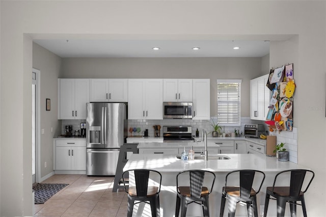 kitchen featuring a breakfast bar, a sink, stainless steel appliances, light countertops, and light tile patterned floors