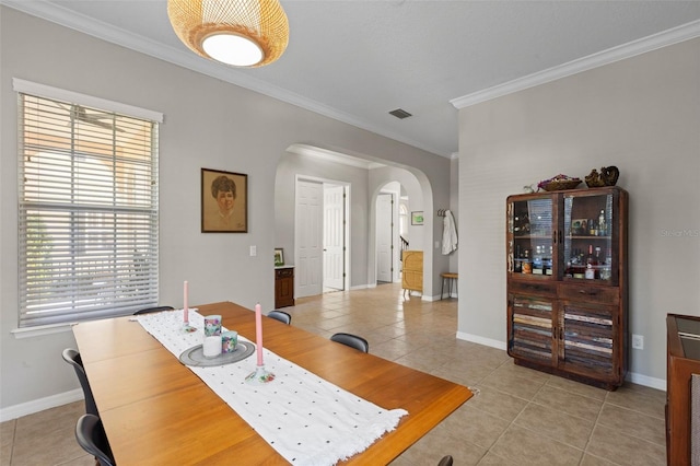 dining room featuring light tile patterned floors, visible vents, arched walkways, and ornamental molding