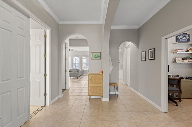 hallway featuring arched walkways, crown molding, baseboards, and light tile patterned flooring