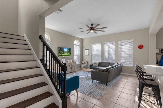 living area with visible vents, baseboards, ceiling fan, stairway, and light tile patterned floors