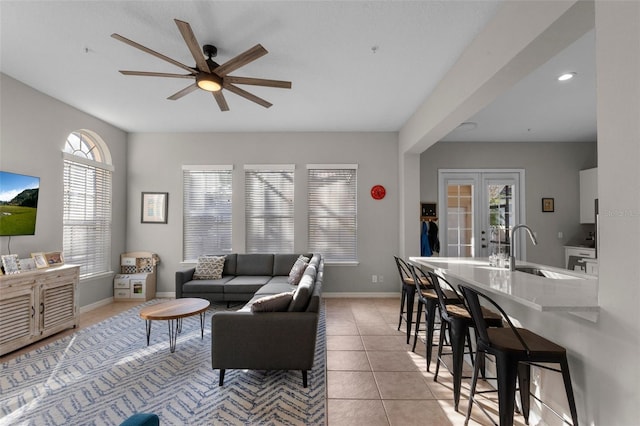 living area featuring light tile patterned floors, french doors, baseboards, and ceiling fan