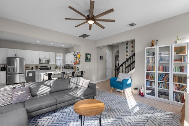 living area featuring visible vents, ceiling fan, stairs, light tile patterned floors, and arched walkways