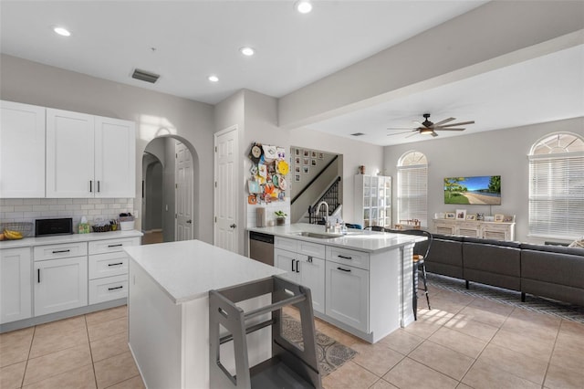 kitchen featuring visible vents, open floor plan, a kitchen bar, plenty of natural light, and a sink