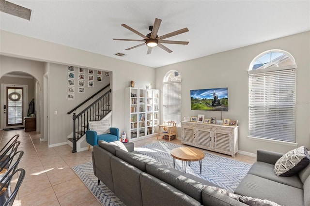 living area featuring visible vents, arched walkways, light tile patterned flooring, and a ceiling fan