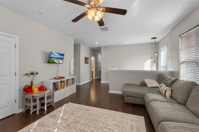 living area with visible vents, a textured ceiling, dark wood-type flooring, and a ceiling fan