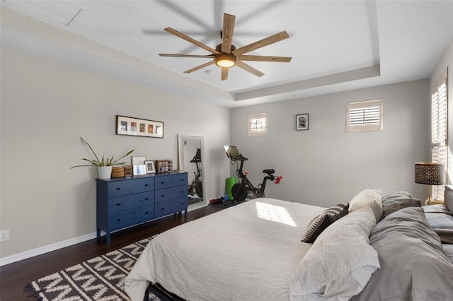 bedroom featuring a ceiling fan, a raised ceiling, baseboards, and dark wood-style flooring