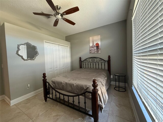 bedroom featuring a closet, ceiling fan, a textured ceiling, and baseboards