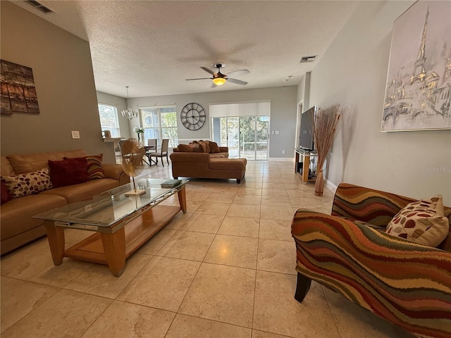 living room with light tile patterned floors, visible vents, a textured ceiling, and ceiling fan