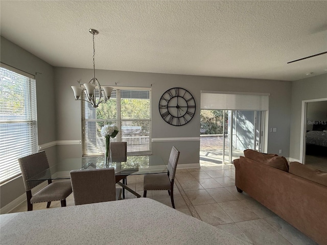 dining space featuring baseboards, plenty of natural light, a notable chandelier, and a textured ceiling