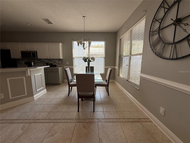 dining room with light tile patterned floors, baseboards, visible vents, an inviting chandelier, and a textured ceiling