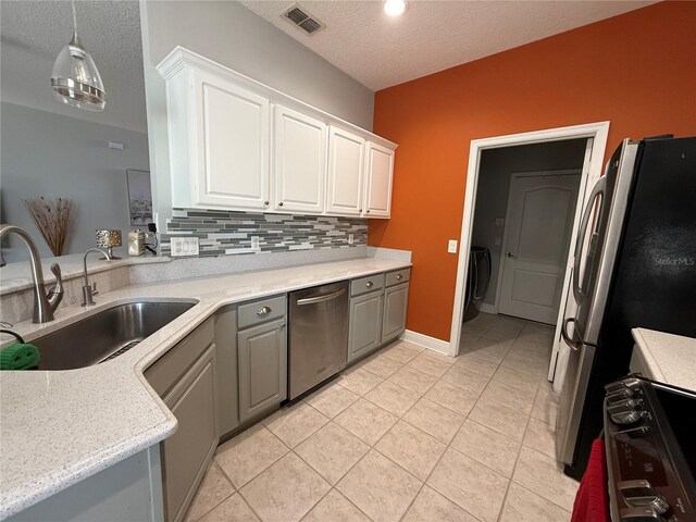 kitchen featuring visible vents, gray cabinets, a sink, backsplash, and appliances with stainless steel finishes