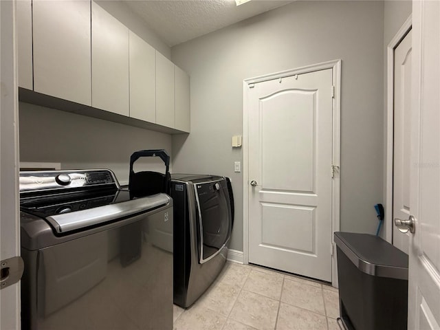 clothes washing area featuring baseboards, light tile patterned floors, cabinet space, a textured ceiling, and separate washer and dryer