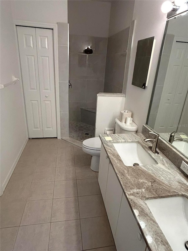 bathroom featuring tile patterned flooring, a walk in shower, toilet, double vanity, and a sink