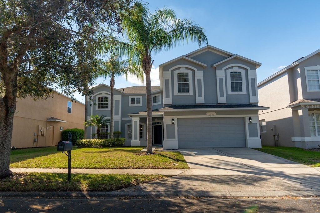 traditional home with a front yard, an attached garage, driveway, and stucco siding