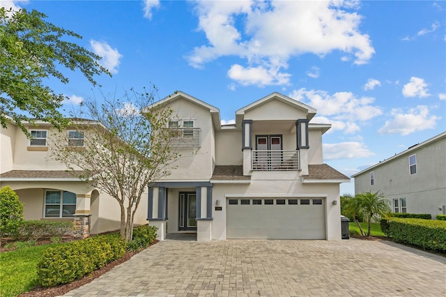 view of front of property featuring a balcony, stucco siding, decorative driveway, and a garage