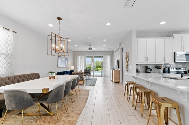 dining room featuring ceiling fan with notable chandelier, light wood-style flooring, recessed lighting, and visible vents