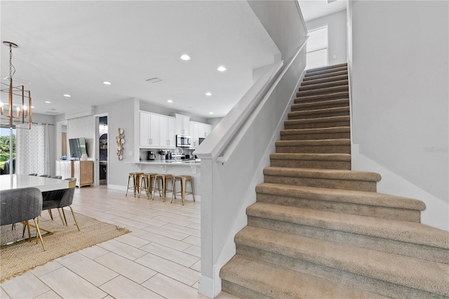 staircase with recessed lighting and a notable chandelier