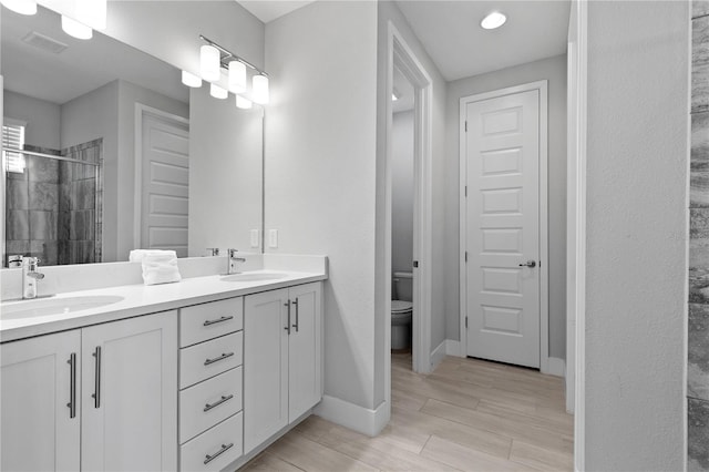 bathroom with a sink, visible vents, toilet, and a shower stall