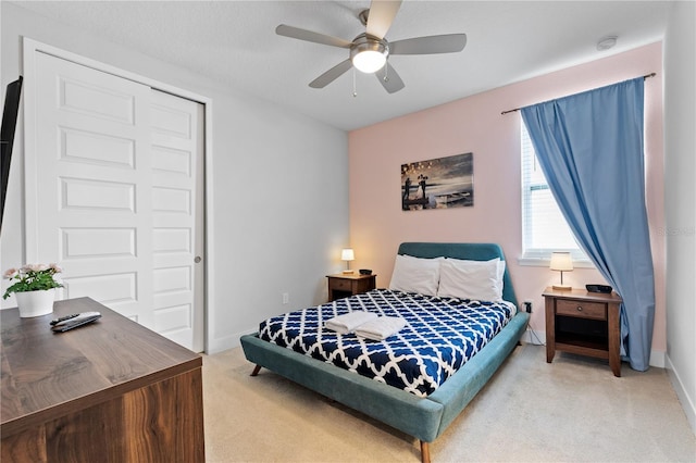 bedroom with ceiling fan, baseboards, a closet, and light carpet