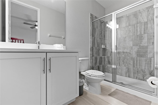 full bathroom with toilet, a stall shower, vanity, and ceiling fan
