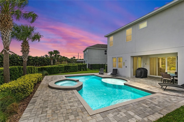 pool at dusk with a patio, fence, a pool with connected hot tub, and a grill