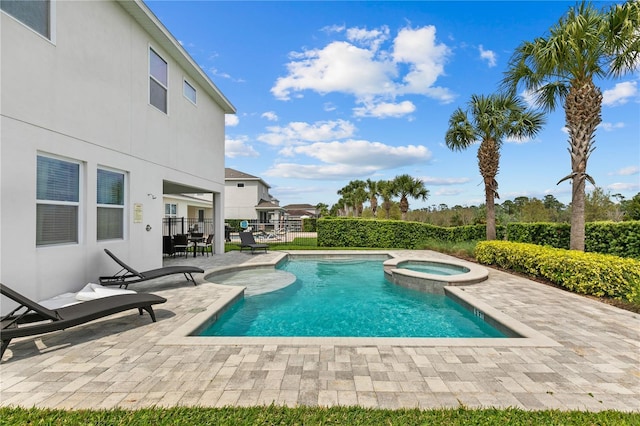 view of pool featuring a pool with connected hot tub, a patio, and fence